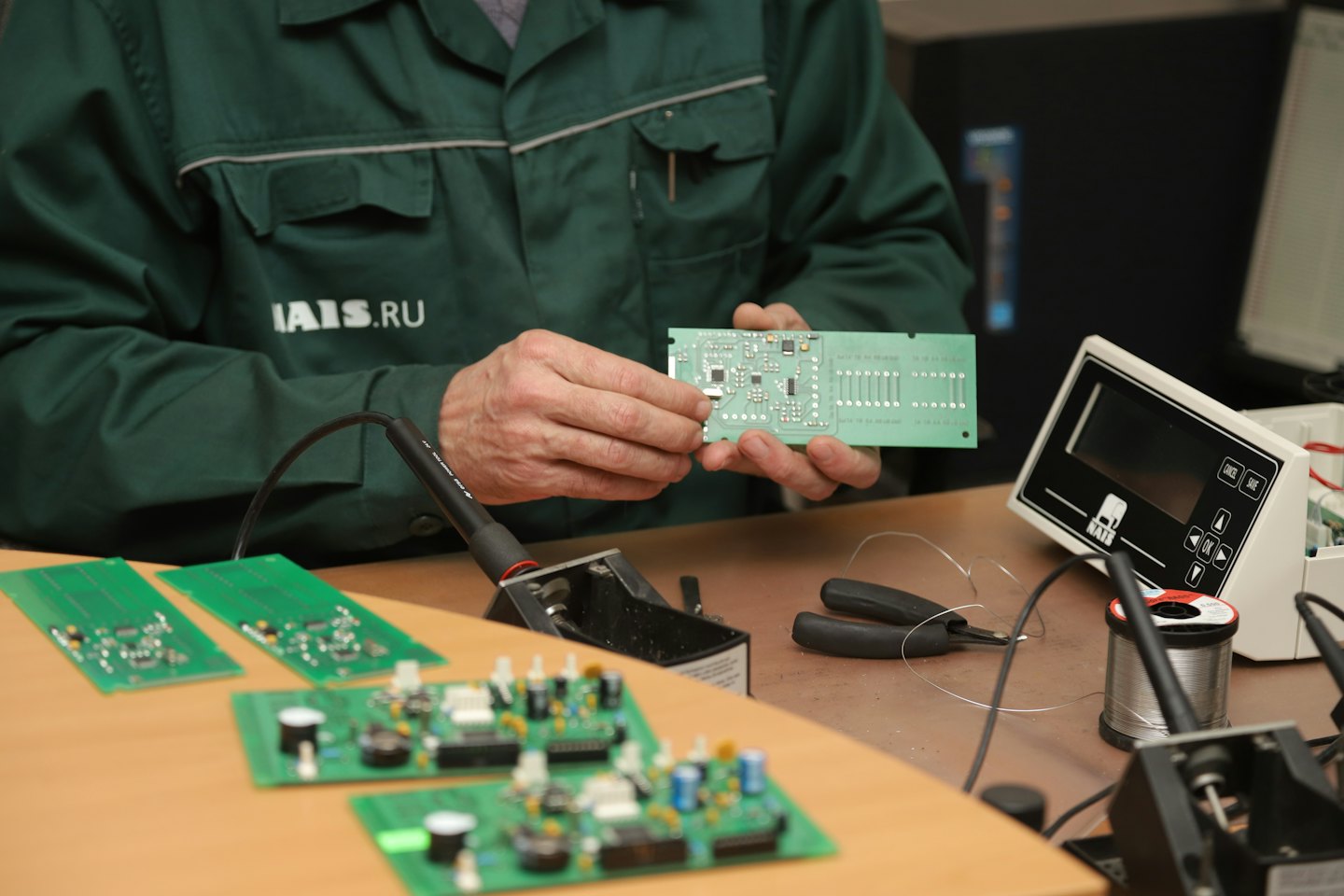 Ingegnere esamina un circuito stampato con microchip su un banco da lavoro.