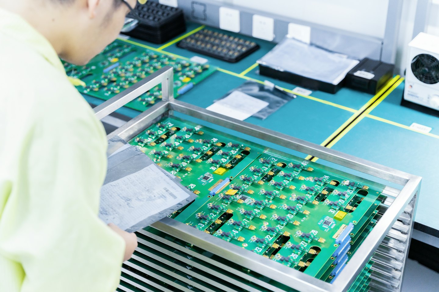 Uomo in camice da laboratorio che ispeziona file di schede elettroniche.